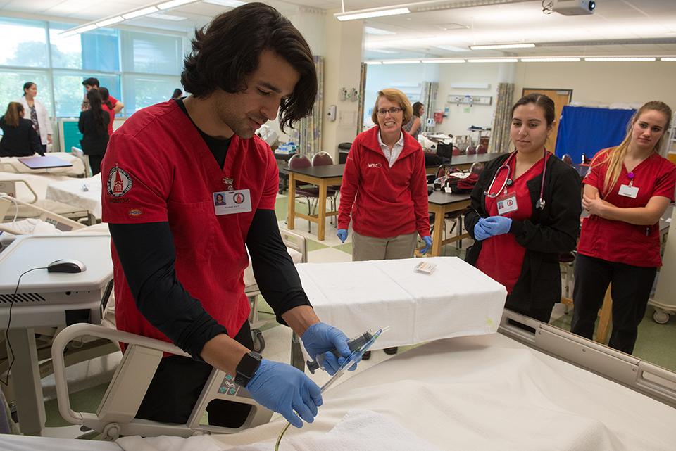 Nursing students around a hospital bed